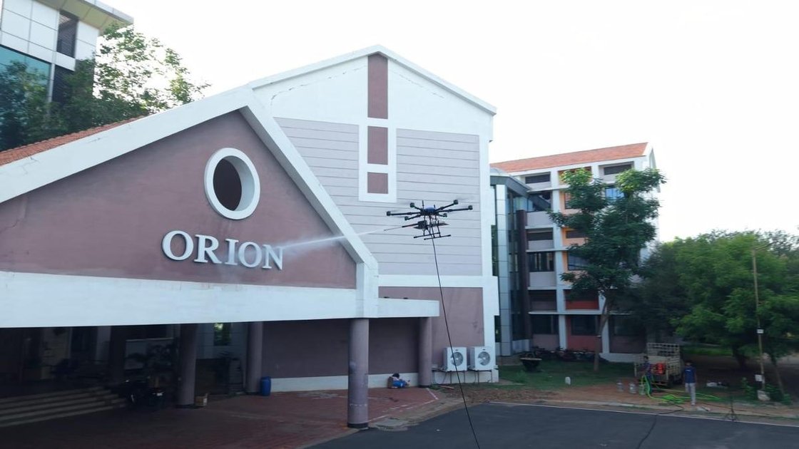 Zerowings Aerospace का फेकाडे-वॉशिंग ड्रोन NIT-T में प्रदर्शन के दौरान इमारत की दीवार साफ करता हुआ