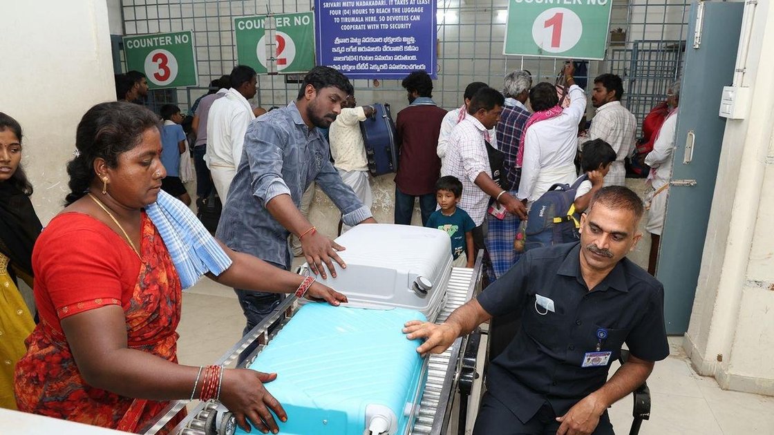 TTD कर्मचारी तिरुपति में जमा काउंटर पर तीर्थयात्रियों के सामान की स्कैनिंग करते हुए