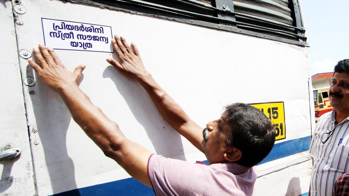 केरल में प्रियदर्शिनी योजना के शुभारंभ पर KSRTC बस पर स्टिकर लगाते कार्यकर्ता