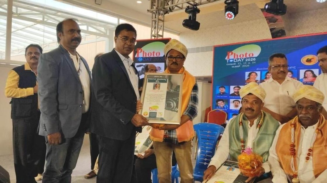 फोटो पत्रकार पुंडलिक के. बडिगर को कर्नाटक वीडियो एंड फोटो एसोसिएशन और कर्नाटक स्टेट प्रेस फोटोग्राफर एसोसिएशन द्वारा पुरस्कार प्राप्त करते हुए दिखाती तस्वीर