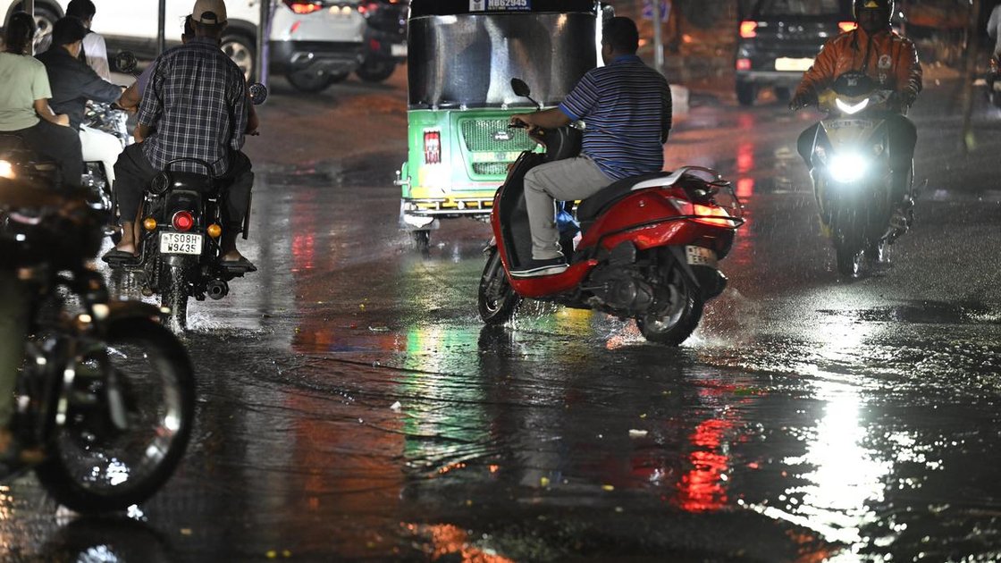 सिकंदराबाद में बारिश के दौरान लोग चलते हुए