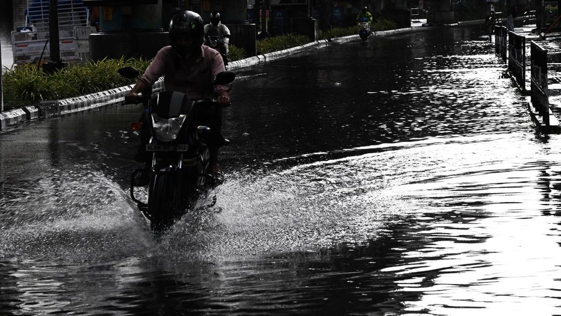 केरल में भारी बारिश के दौरान सड़क पर पानी भरा हुआ, लोग छाता लेकर चल रहे हैं