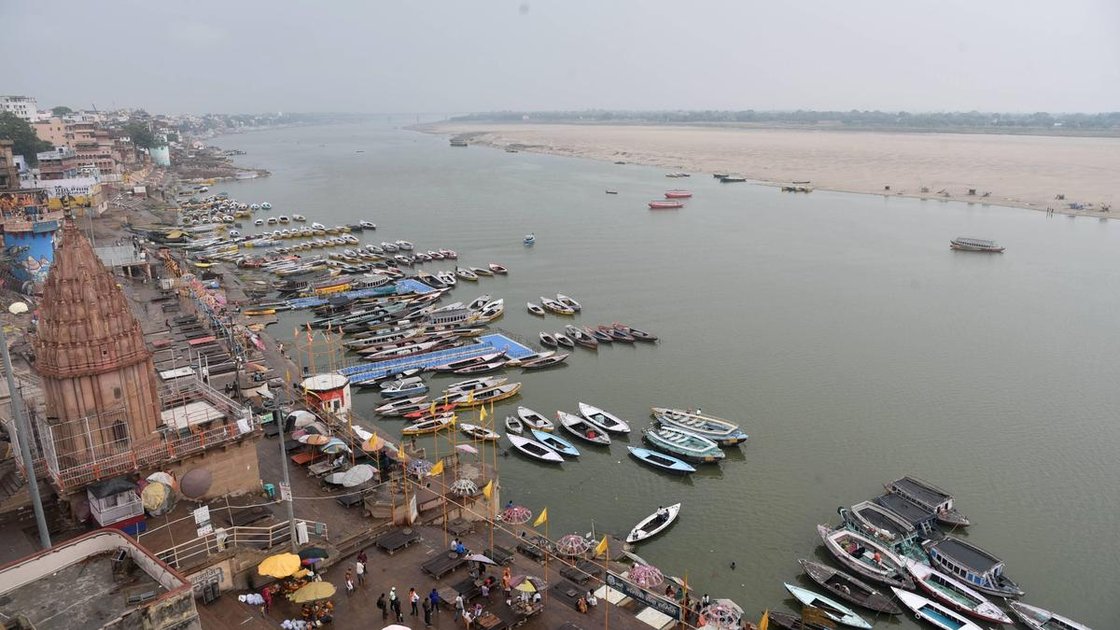 वाराणसी में गंगा घाट का दृश्य, बारिश के बीच नावें खड़ी हैं