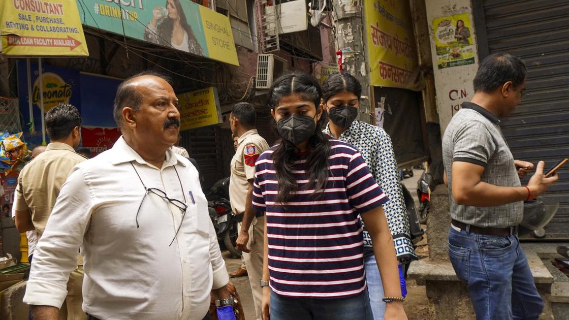People gather near a five-storey residential building where a fire killed three and injured eight in Tughlakabad Extension, New Delhi, June 12, 2026.