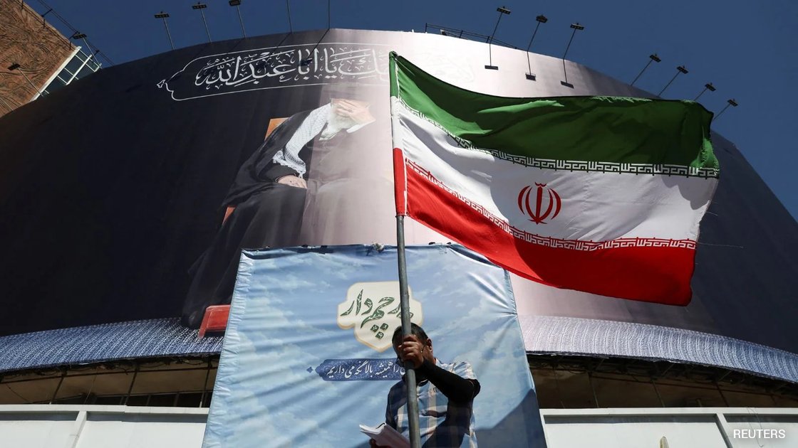 US and Iranian officials shaking hands at a peace deal signing ceremony in Geneva, with flags in background