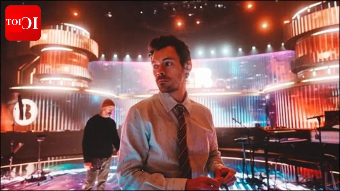 Harry Styles performing on stage with David Hockney's digital artwork as backdrop at Wembley Stadium